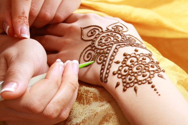 Een schoonheidsspecialiste brengt een henna-tatoeage aan op de arm van een vrouw